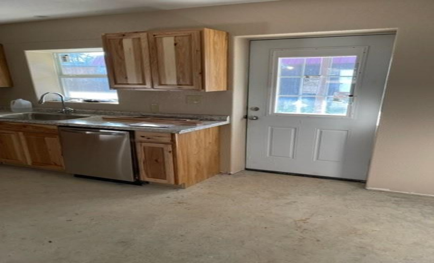 Another view of the kitchen area showing dishwasher and exit onto the covered porch.