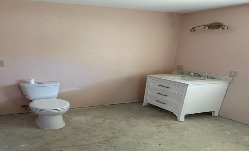 Commode and vanity off second bedroom  is a large bathroom with a large closet.