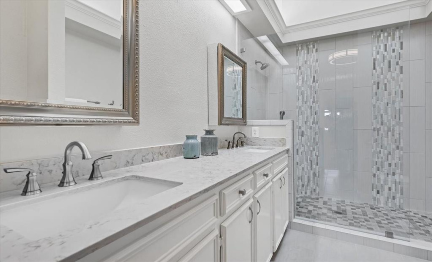 Primary bathroom features two sinks, oversized walk in shower and walk in closet.