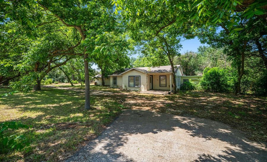 Front view featuring long drive with 40’+ trees providing a wooded view and plenty of shade during the hot summers. _1 ACRE FOR SALE: 2923 Pecan Springs Rd., Austin, Tx 78723