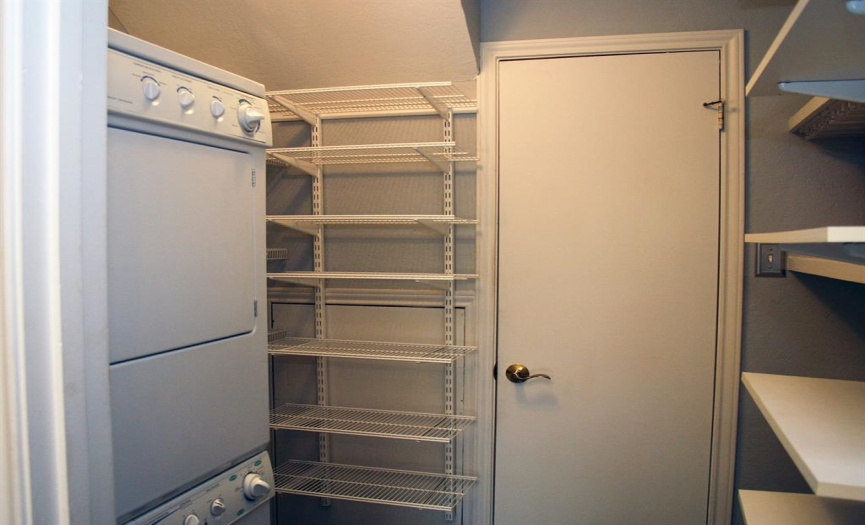 The utility area can accommodate a full-size washer/dryer, but the owner realized a stackable set would boost easily accessible shelving. (The adjacent door conceals the water heater and a new A/C unit.