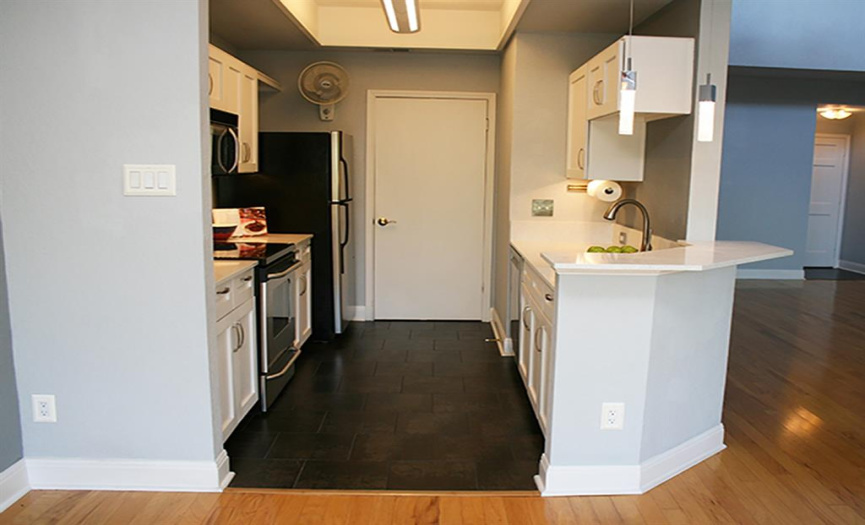 The galley kitchen has been remodeled from top (sleek LED fixture in light chase) to bottom (dark tile with a silvery wash).  Sandwiched between: updated white cabinets with sparkly white quartz counters.