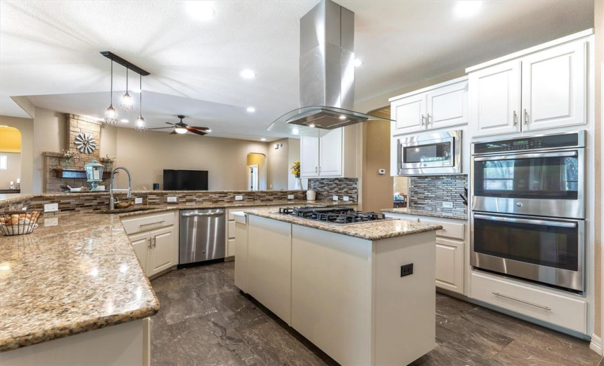 The stainless appliances, decorative tile backsplash, recessed and pendant lighting add to the appeal of the kitchen.