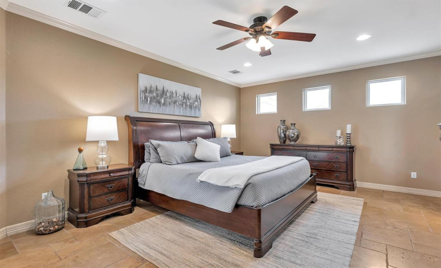 The primary bedroom has easy-to-care-for tile flooring, a ceiling fan recessed lighting and crown molding.
