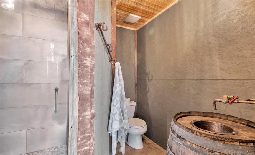The attached bath, through the barn door, has a custom barrel and copper sink with vintage faucets. The same detail can also be seen in the shower.