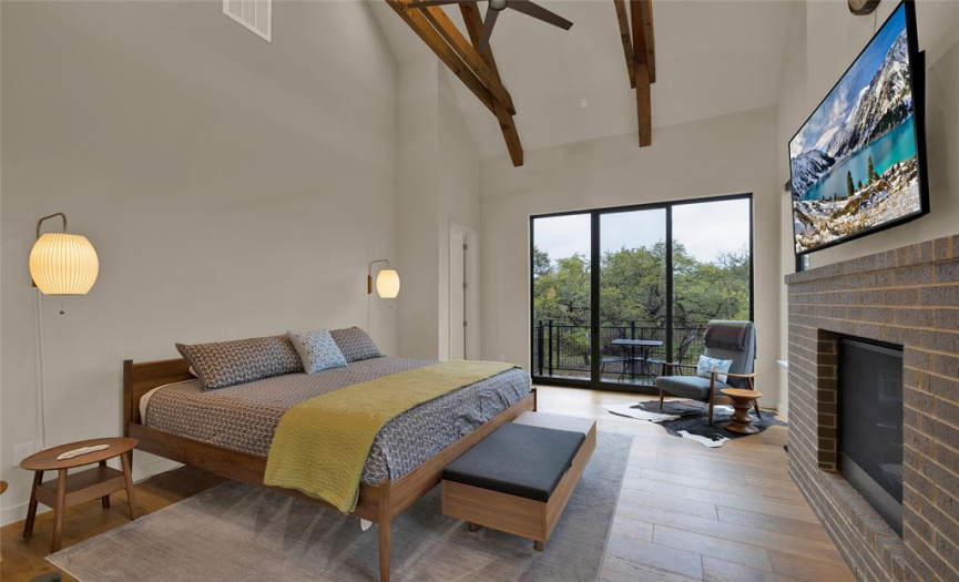 Main bedroom with a step out balcony overlooking the Hill Country.  Large wood beams accenting the room.  Do not miss the beautiful fireplace.  