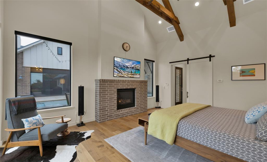 View in main bedroom showing the fireplace, and the barn door entry. Views of the pool from the windows. 
