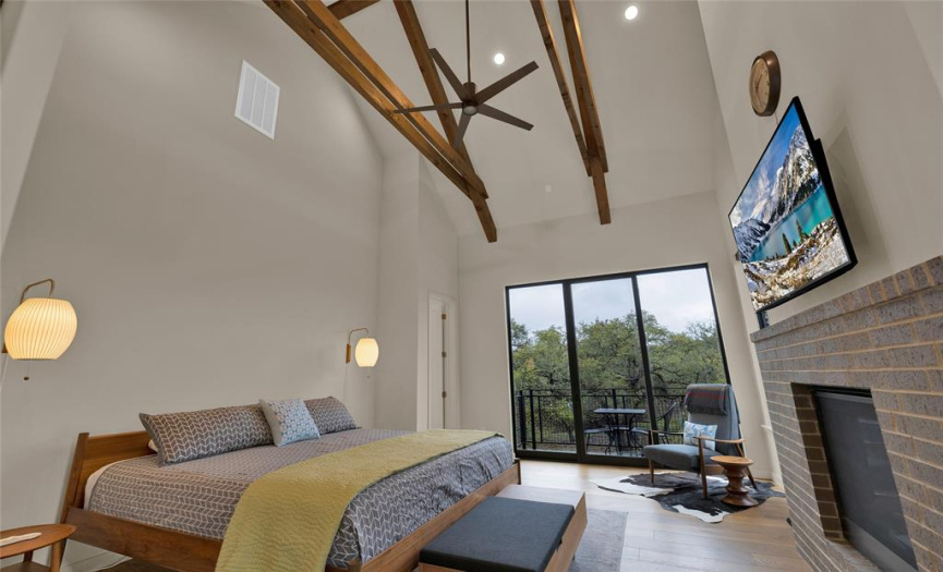 Main Bedroom with high vaulted ceilings with wood beams. Private main bedroom fireplace, and separate balcony.   