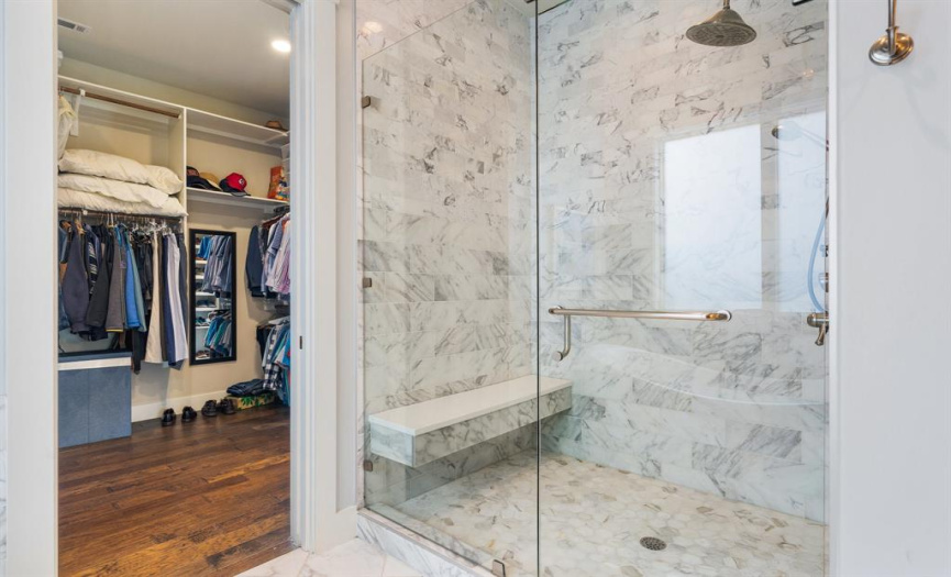 Step into the shower for the ultimate relaxation with a rainfall showerhead, frameless glass enclosure, custom tile and a bench seat