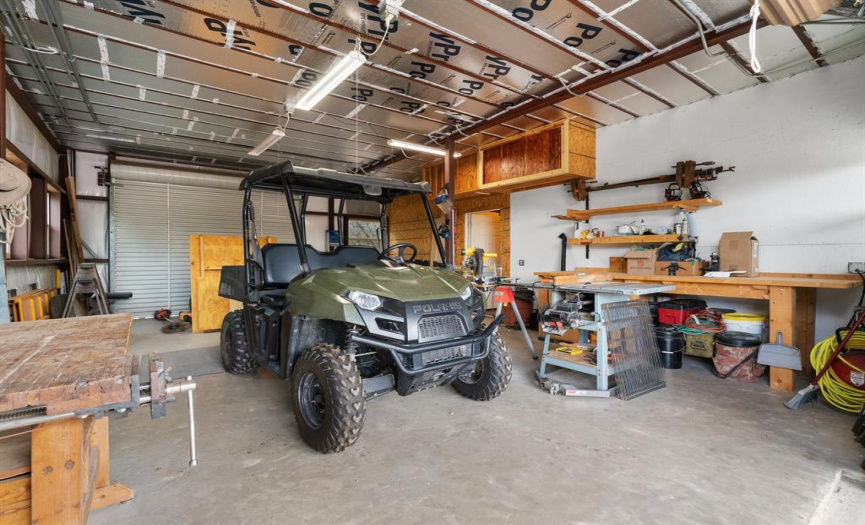The awesome garage workshop has doors on both sides plus work benches and storage shelving.