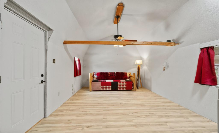 The well-designed studio apartment features wood-look vinyl plank flooring, tall ceilings, and beautifully stained exposed beams.
