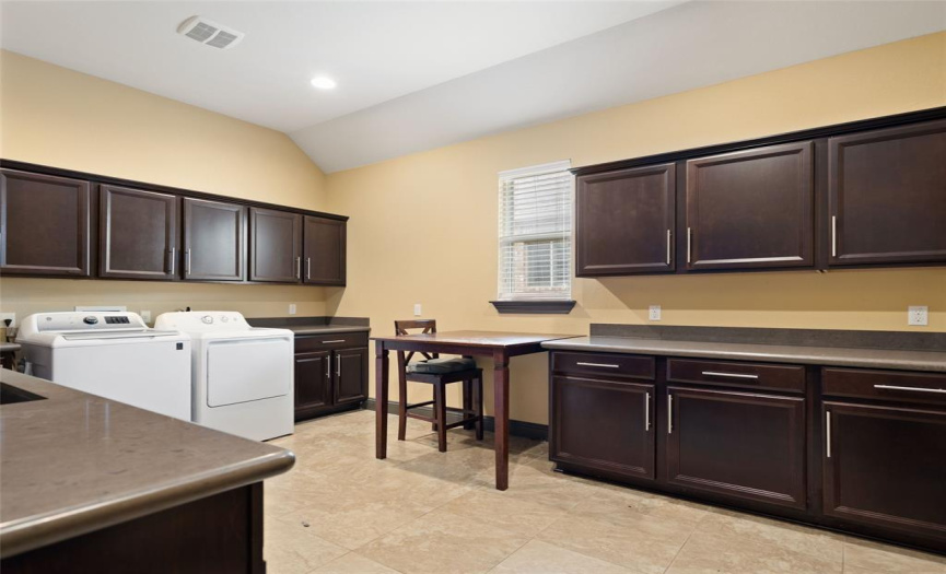 Oversized utility room with sink and multiple cabinets and countertops. Located right off the kitchen.
