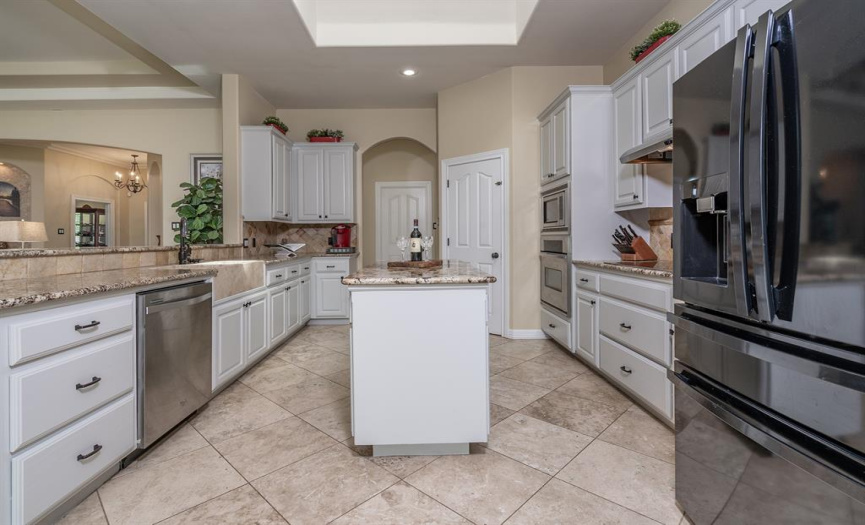 Kitchen with granite and stone farm sink, Island, skylight, built in stainless appliances.