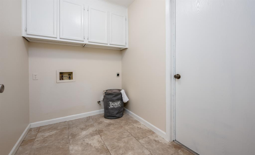 Laundry room with tile flooring and upper cabinetry 