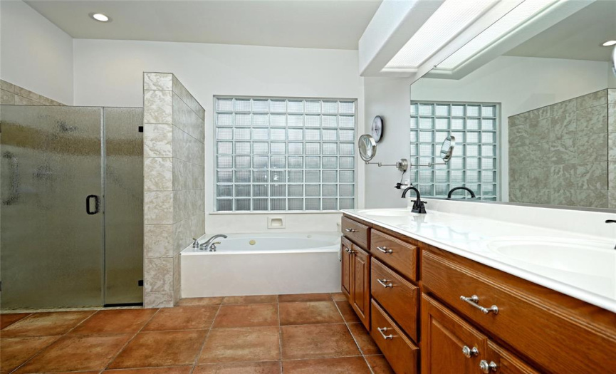 Main bathroom with dual vanity plus a jetted garden tub and  an updated frameless glass standup shower.