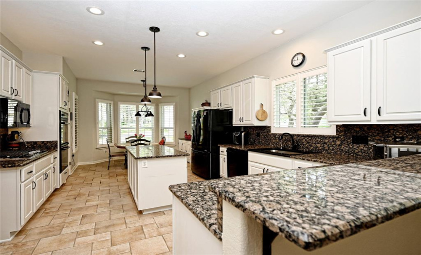Kitchen has been nicely updated with recessed and pendant lighting, granite counters and wonderfully white cabinets with black pulls.