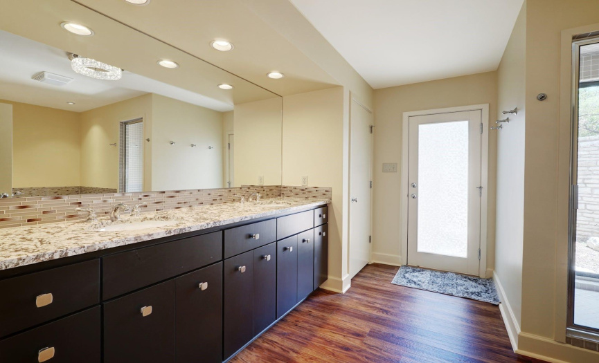 Double sinks, granite countertops and mosaic tile backsplash create a lovely owner's suite bath
