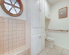The primary bathroom has plenty of storage and a unique round window trimmed in beautiful oak, and the lovely pink tile extends past the bathtub to create a bench seat. 