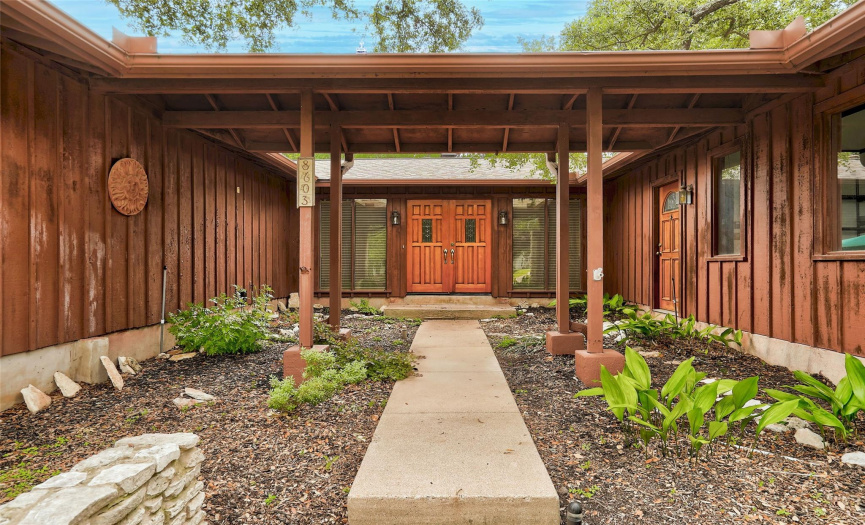 Inspired by Frank Lloyd Wright, your stylish entrance is enhanced with a roof covering whcih joins both sides and gorgeous wood double doors into the house. 