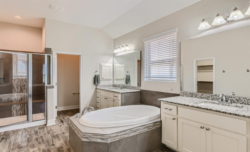 Primary bathroom offers a soaking tub, walk-in shower and separate vanities