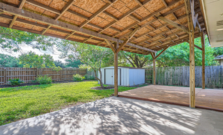 Landscaped backyard includes covered patio/porch and a metal building for your lawn tools/lawnmower.