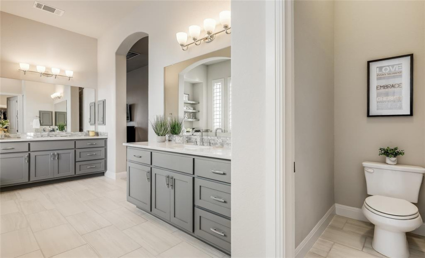 Separate vanities offer abundant storage and host cultured marble counters.