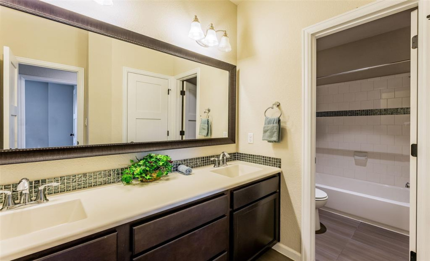 shared bathroom upstairs with dual vanities and separate shower/toilet room