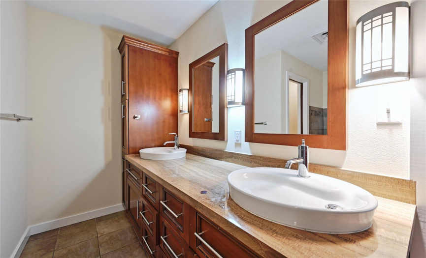 Experience luxury in the master bathroom with its elegant dual vanity adorned with beautiful wood cabinets. These stylish fixtures provide ample storage space for your essentials. The well-placed lights illuminate the area, creating a warm and inviting ambiance. 