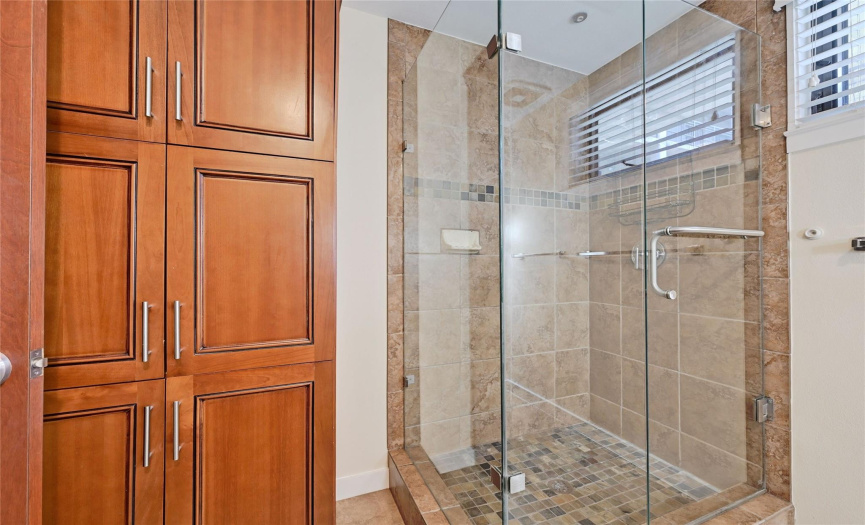 Discover the stylish second bathroom featuring a sink, mirror, tasteful tiles, fresh paint, a frameless shower, a small window for natural light, a well-placed light fixture, and convenient bath towel poles. 