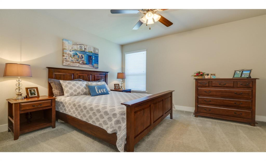 Spacious secondary bedroom with ceiling fan and views to the backyard.