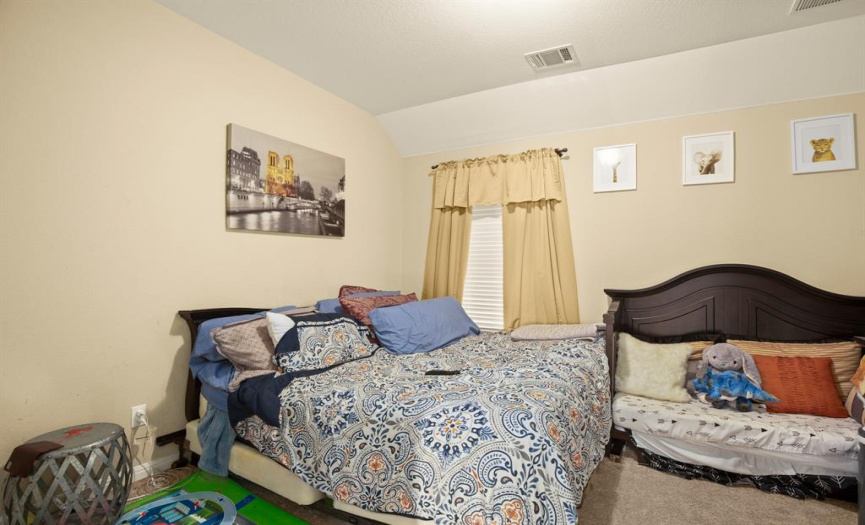 This bedroom has high ceilings and carpet flooring throughout.