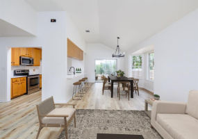 Enter into an open concept living/dining/kitchen area with a far view to the back slider (covered patio and view of nature to the back side of the property). Virtually staged.