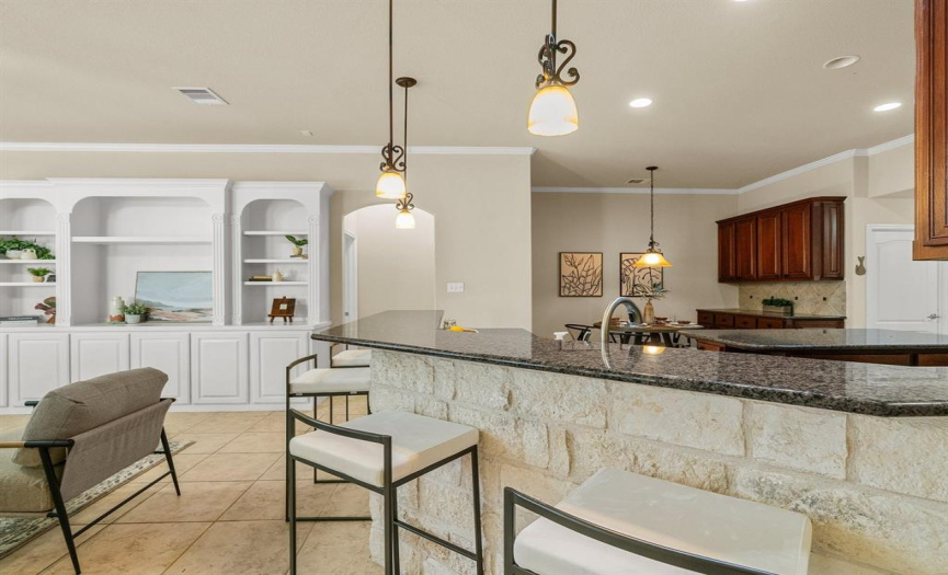 Indulge in the exquisite craftsmanship of the custom stone detailing that beautifully frames the breakfast bar, seamlessly matching the surrounding stone around the cooktop