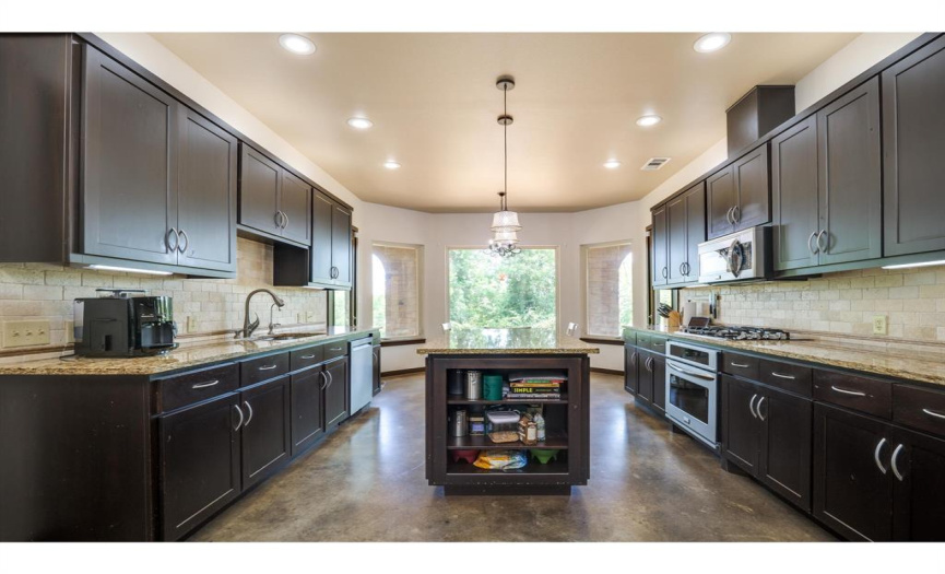 The chef's kitchen is well-appointed with granite countertops, stone backsplash, stainless steel appliances, and plenty of storage to satisfy your culinary aspirations