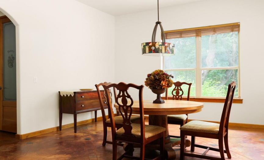 Light filled dining room with views of nature and stained concrete floors.