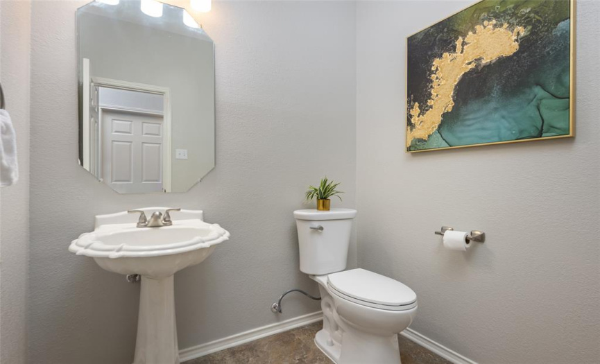 Roomy half bath is smartly located off the garage door entry and directly across from the laundry/utility room