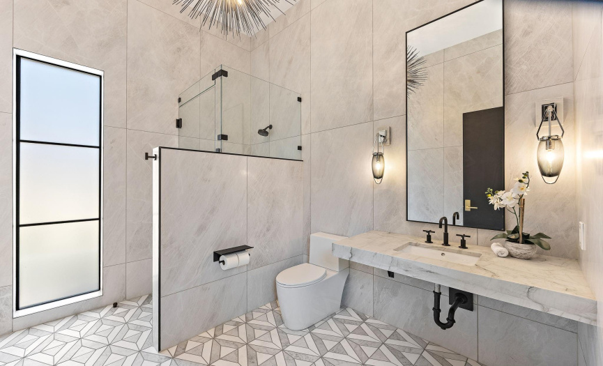 Downstairs bath with Italian marble floors full shower and sputnik chandelier