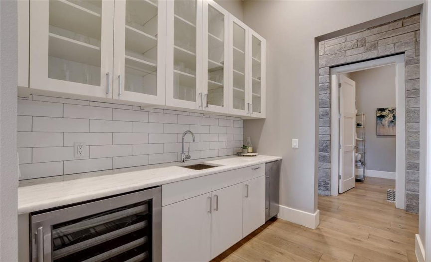 Butlers pantry/wet bar is perfectly placed off of the kitchen equipped with ample storage, a wine refrigerator, and ice maker.