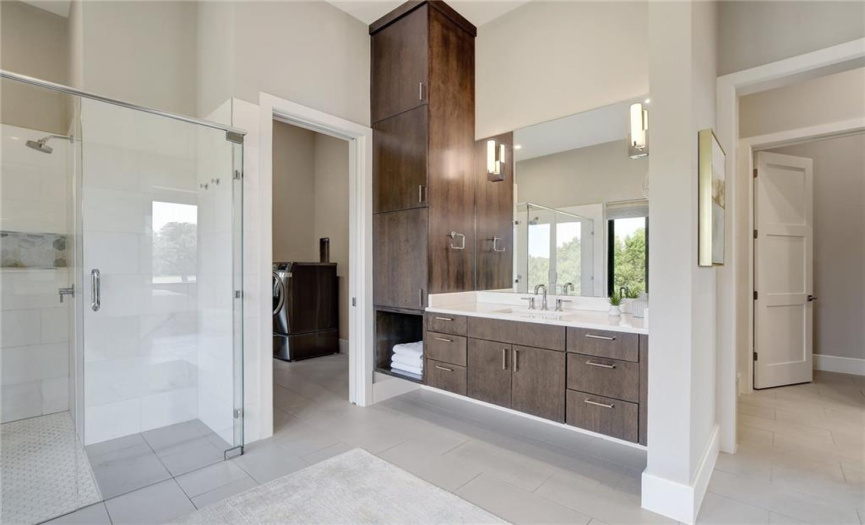 Dual vanities in the primary bath with extensive storage and spa like appeal. Fully equipped laundry room offers added convenience to primary suite. 