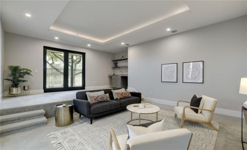 Secluded multi-level media room equipped with a built-in wet bar which opens to a private patio