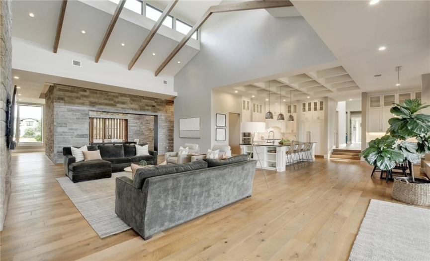 Soaring, vaulted ceilings, in the great room, are accented with custom wood beams highlighting a row of architectural transom windows on each side. 