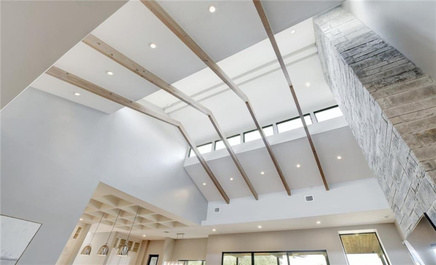 Soaring, vaulted ceilings, in the great room, are accented with custom wood beams highlighting a row of architectural transom windows on each side. 