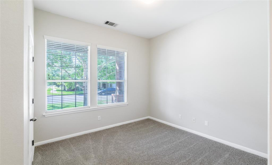 Bedroom 2 is on the main level and has two-inch blinds, a ceiling light, standard closet, an adjacent full bath, and measures approximately 10 x 11.