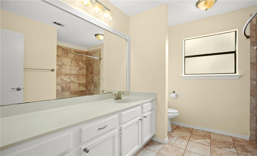 The guest bathroom has a large single vanity and a tub/shower combo.