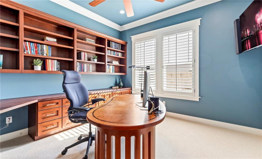 Glass panel french doors off the entry lead to a dedicated home office complete with crown molding, recessed lighting, a ceiling fan, built-in bookcases, and a built-in work station - perfect for those who work remotely!