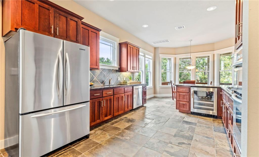 The kitchen is equipped with high-end stainless-steel appliances including a gas cooktop, a built-in oven, and a wine refrigerator!