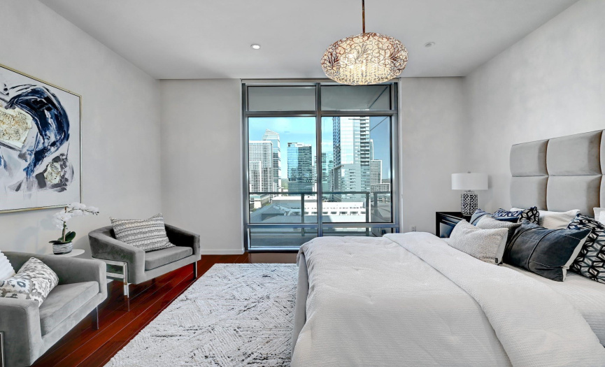 The bedroom exudes comfort, with a sparkling light fixture and custom shades