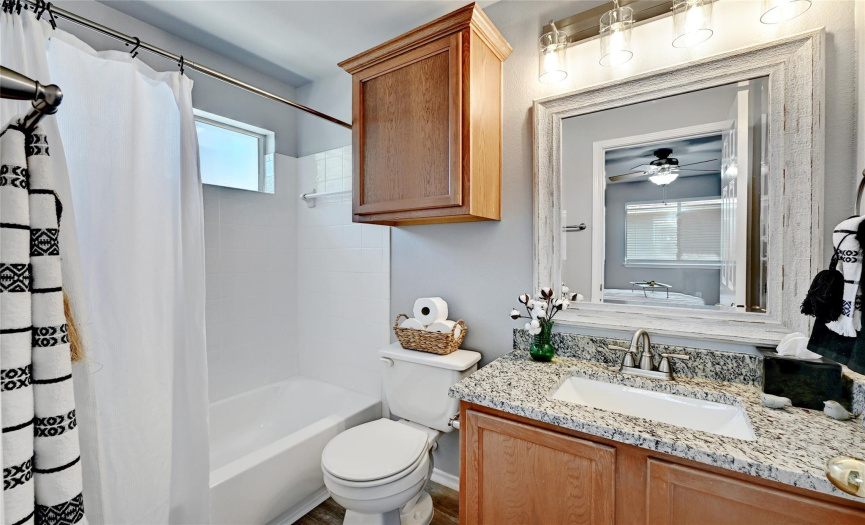 Primary bathroom with updated lighting, granite countertop, and new mirror.