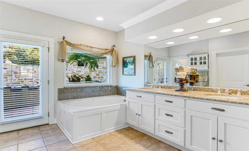 Double, granite topped vanities, large walk-in shower and a jetted soaking tub are highlights of the luxurious primary bath. (Note: door in photo leads to a courtyard patio.)