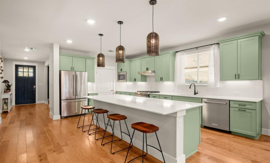 The centrally located kitchen boasts a grand center island, a breakfast bar, quartz countertops, undercabinet lighting, and a classic subway tile backsplash.